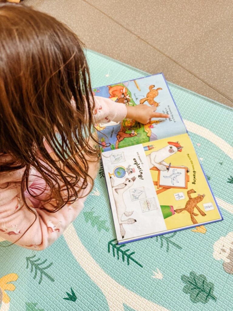 Girl pointing to the text in a picture book as she is learning to read