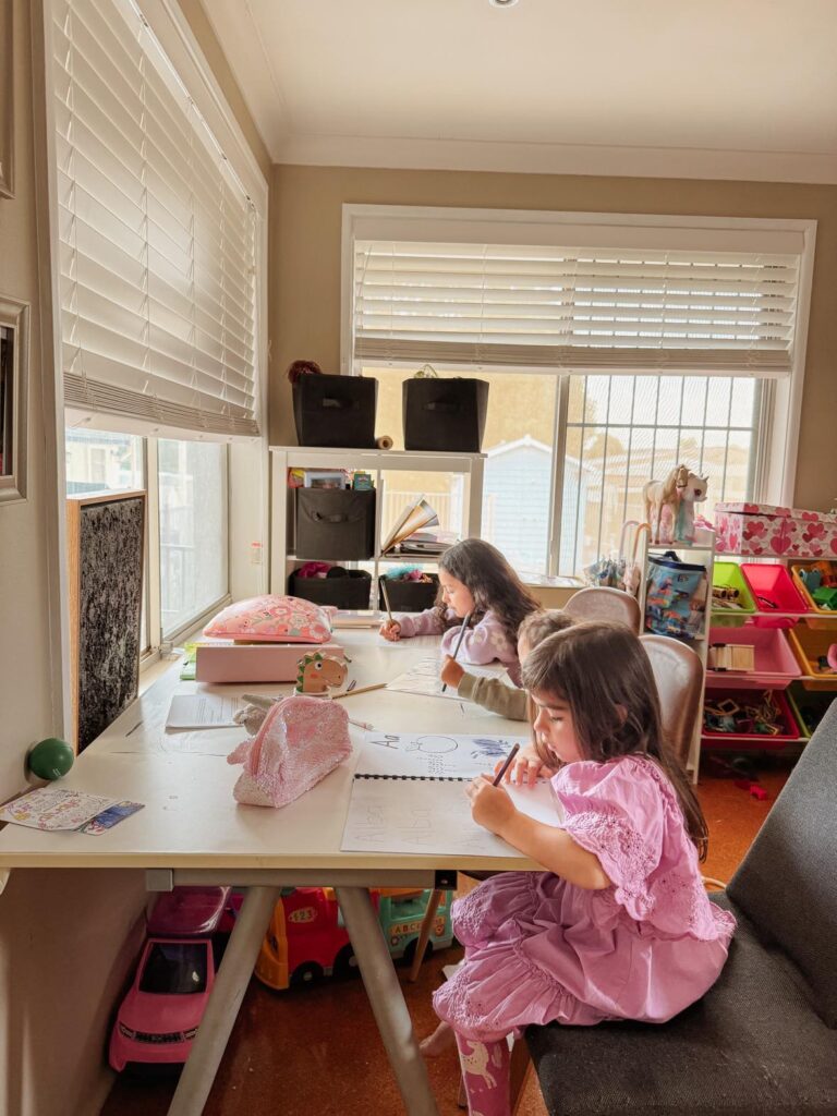 Three kids sitting at the homeschool table doing book work