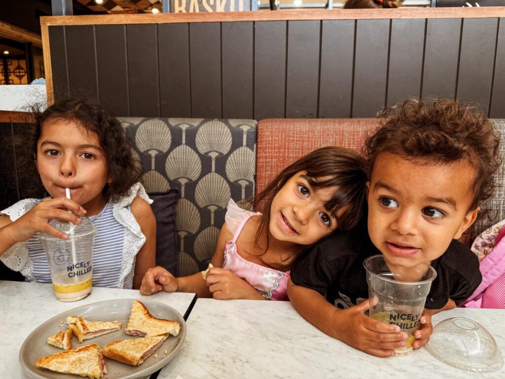 How to overcome challenging homeschool days: three children sitting at cafe smiling and drinking a cold drink.