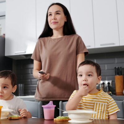 A mother with her young sons enjoying a meal in a modern kitchen setting.